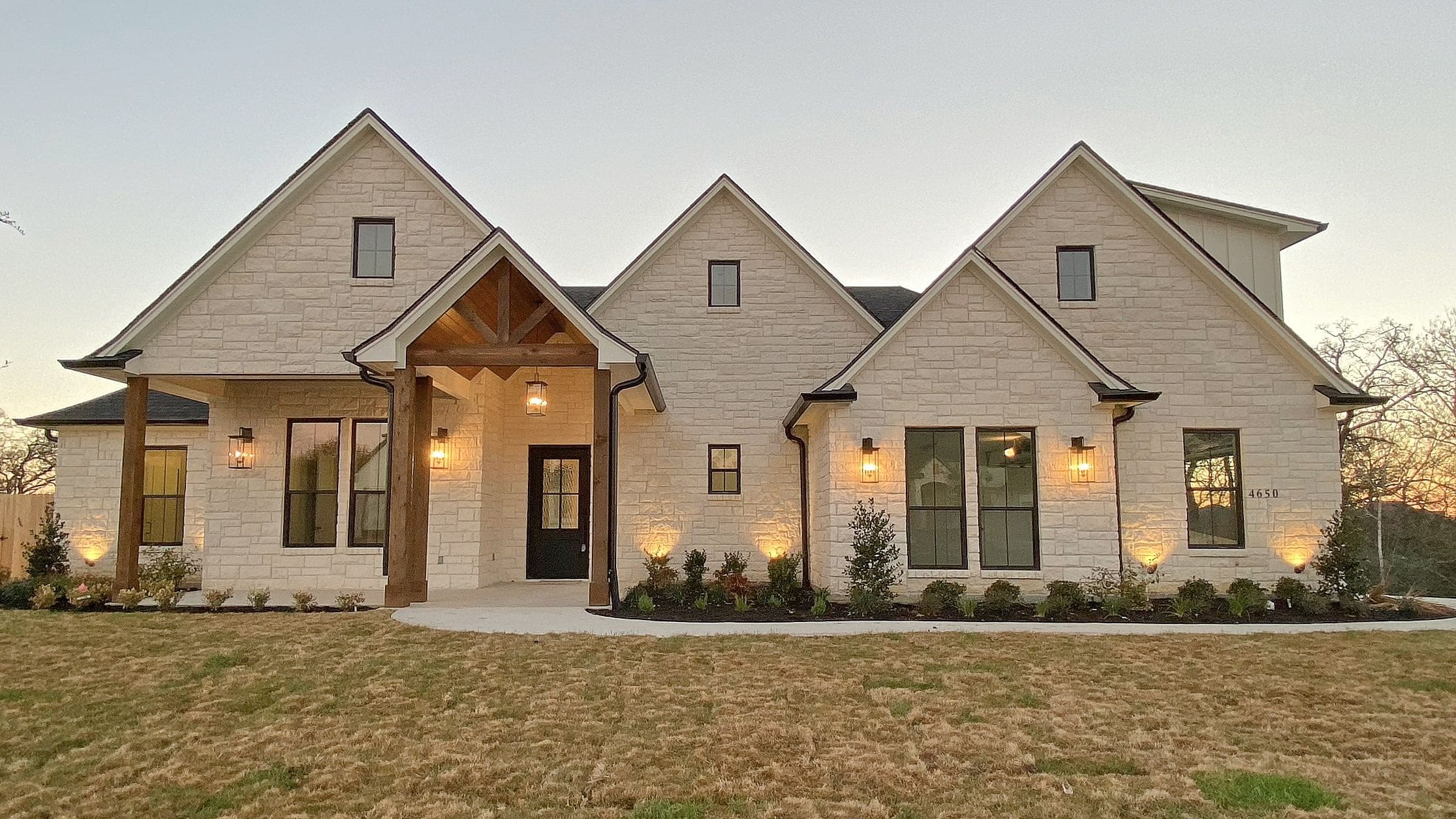 Newly built modern house with stone exterior and multiple gabled roofs in a suburban area.