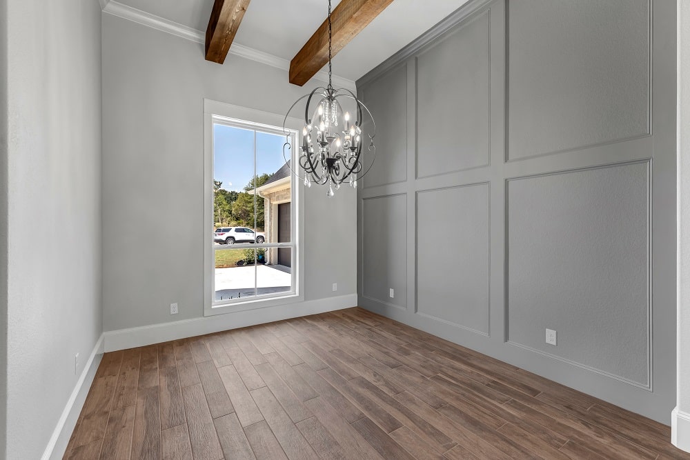 Empty room with gray walls, wooden beams, and a chandelier, in a house in M3 Construction's service area.
