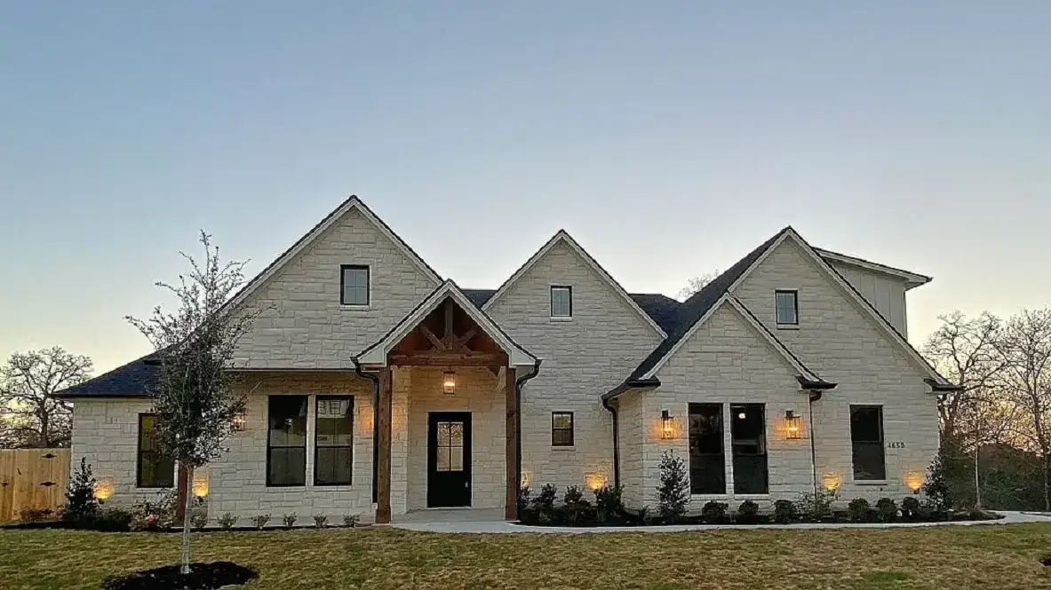 Newly built white house with multiple gables and front porch in a suburban neighborhood.